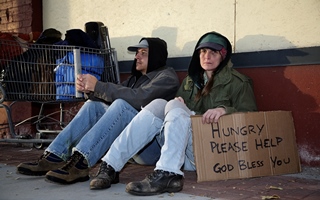 Image of two homeless people sitting on the street